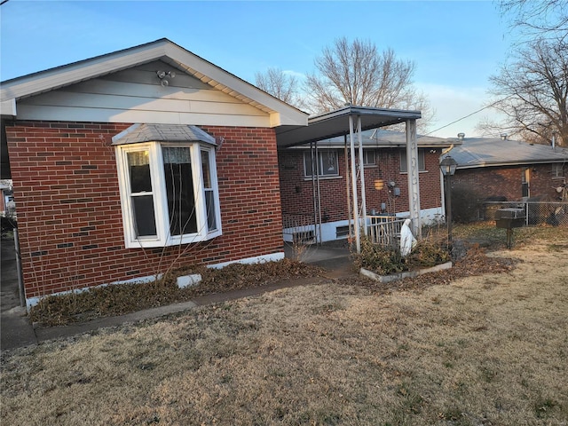 exterior space featuring brick siding, a front yard, and fence