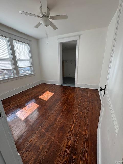 unfurnished bedroom featuring a closet, ceiling fan, baseboards, and wood finished floors