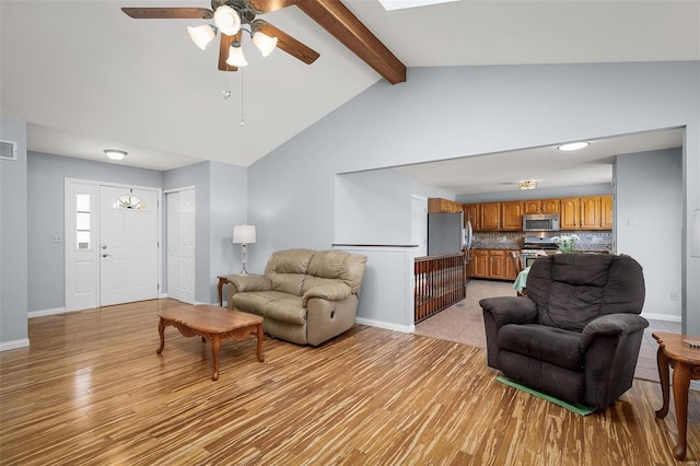 living room featuring visible vents, baseboards, vaulted ceiling with beams, and light wood finished floors