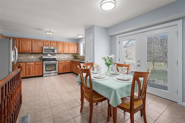 dining space with light tile patterned floors, visible vents, and french doors