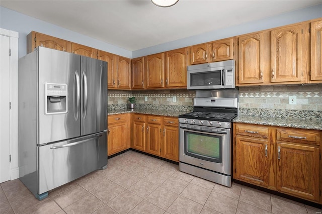 kitchen featuring light tile patterned floors, brown cabinetry, and stainless steel appliances