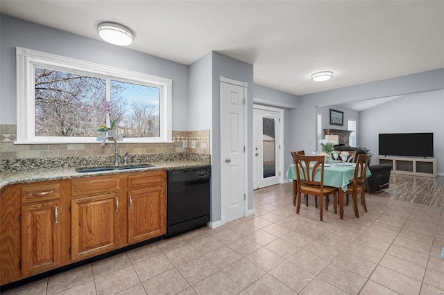 kitchen featuring light stone countertops, brown cabinetry, a sink, black dishwasher, and backsplash