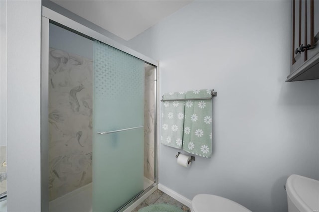 bathroom with a shower stall, toilet, baseboards, and tile patterned floors