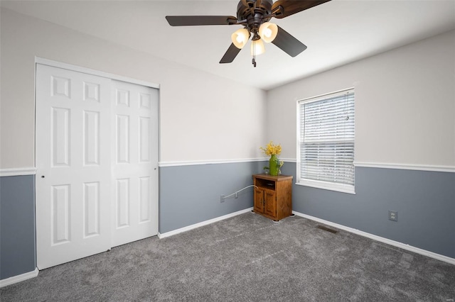 carpeted spare room with visible vents, baseboards, and ceiling fan