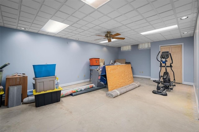 exercise room featuring baseboards, a drop ceiling, and ceiling fan