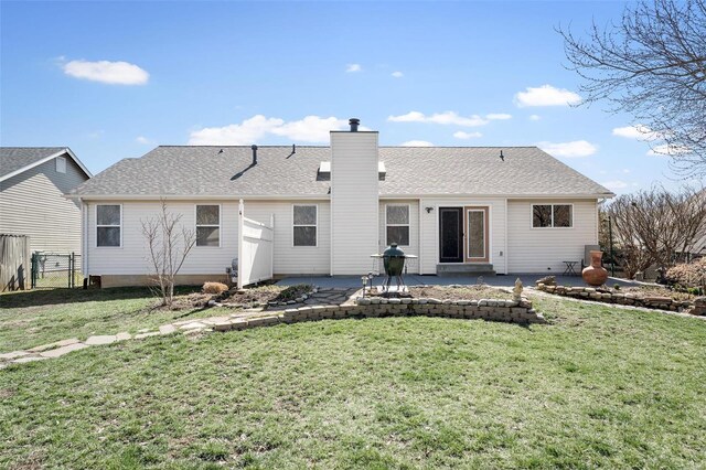 rear view of property with a yard, a chimney, a patio, and fence