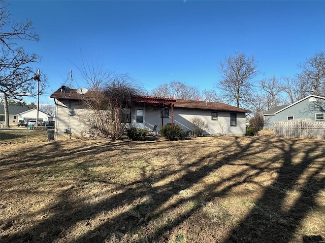 rear view of property with a lawn and fence