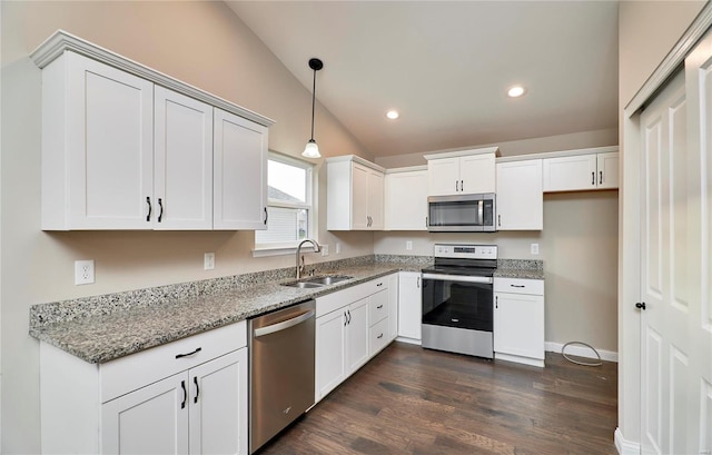 kitchen with light stone counters, lofted ceiling, dark wood-style flooring, a sink, and appliances with stainless steel finishes