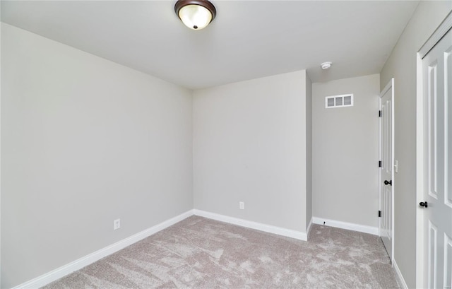 empty room featuring light carpet, visible vents, and baseboards