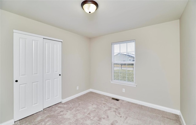 unfurnished bedroom with visible vents, baseboards, light colored carpet, and a closet