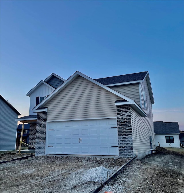 view of front of house featuring an attached garage, brick siding, and driveway