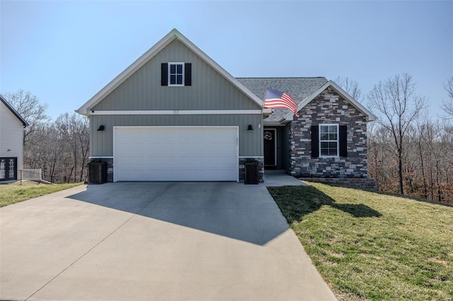 view of front of home with a front yard, a shingled roof, concrete driveway, a garage, and stone siding