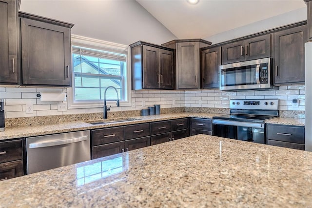 kitchen featuring tasteful backsplash, dark brown cabinetry, vaulted ceiling, stainless steel appliances, and a sink