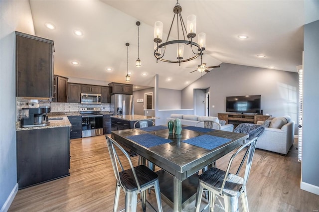 dining room with baseboards, lofted ceiling, light wood-style flooring, and ceiling fan with notable chandelier