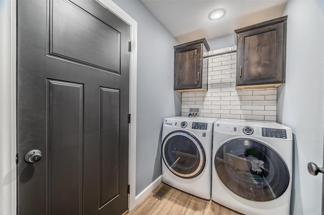 washroom featuring washing machine and clothes dryer, cabinet space, light wood-type flooring, and baseboards