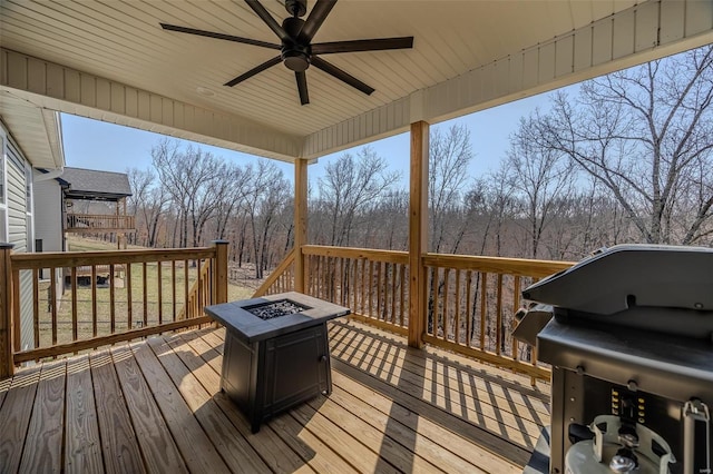 wooden terrace with grilling area, ceiling fan, and an outdoor fire pit