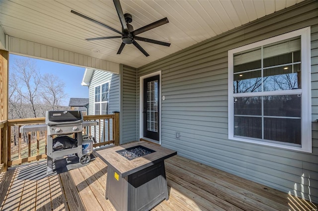 deck featuring grilling area, a fire pit, and ceiling fan