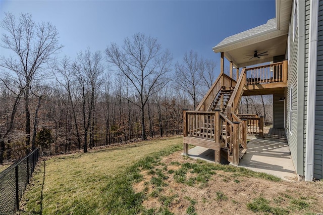 view of yard featuring a deck, a view of trees, fence, stairway, and ceiling fan