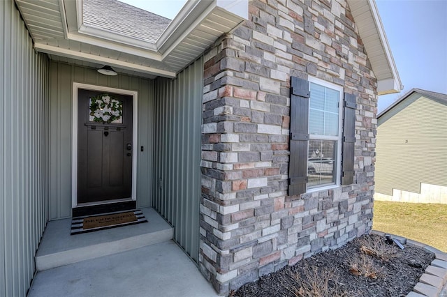 property entrance with stone siding and a shingled roof