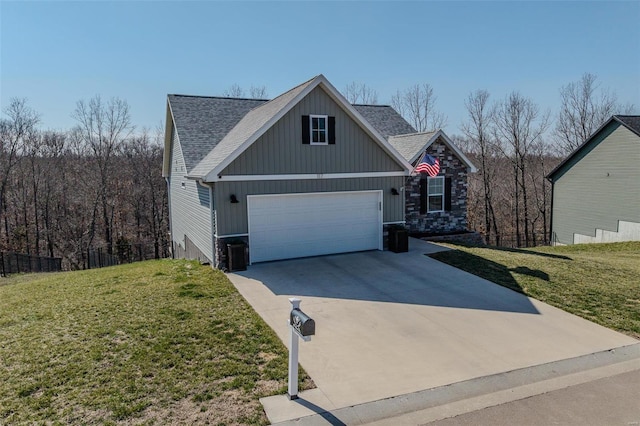 view of front facade with driveway, roof with shingles, an attached garage, a front lawn, and stone siding