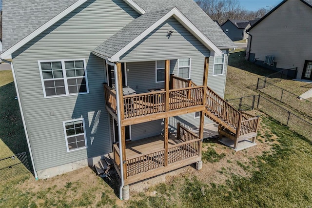 rear view of property featuring a yard, a deck, roof with shingles, and fence