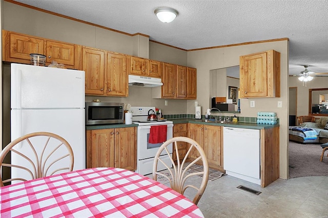 kitchen featuring white appliances, dark countertops, crown molding, and under cabinet range hood