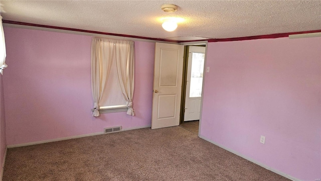 unfurnished room with visible vents, baseboards, a textured ceiling, and carpet flooring