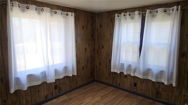 empty room with dark wood finished floors and wooden walls