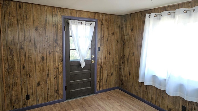 entryway with wooden walls, baseboards, and light wood-type flooring