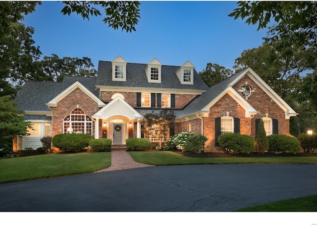 view of front of property featuring brick siding, a front lawn, and a shingled roof