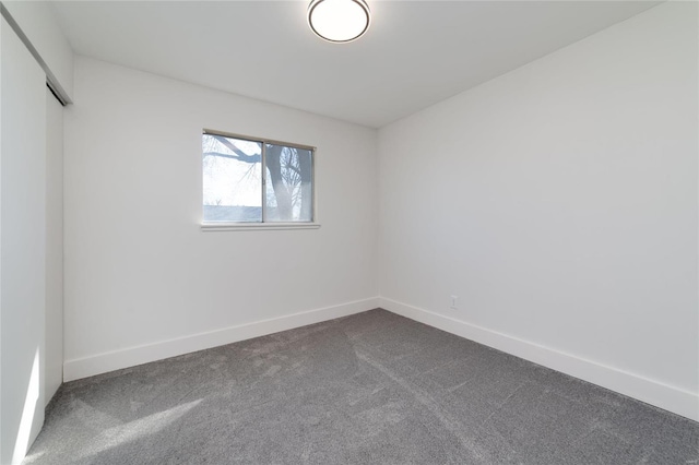 empty room with baseboards and dark colored carpet