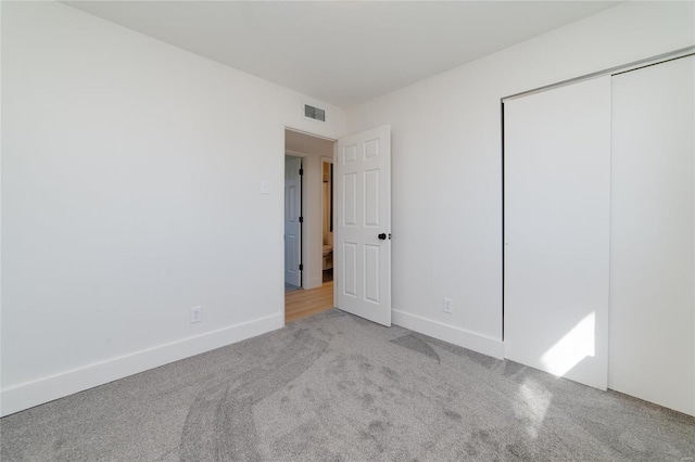 unfurnished bedroom with visible vents, baseboards, carpet, and a closet