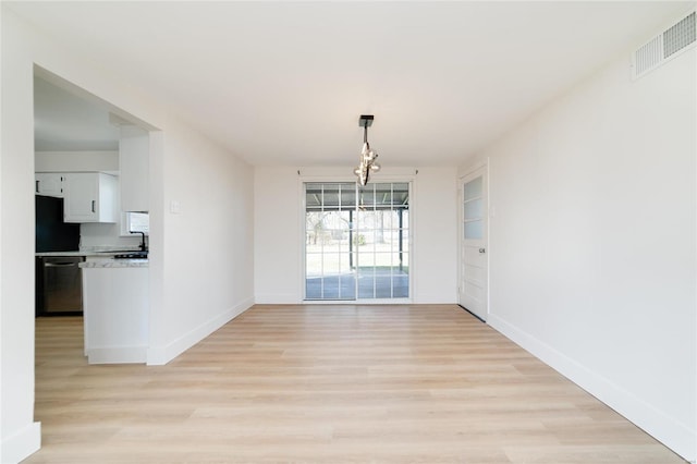 unfurnished dining area with built in shelves, baseboards, visible vents, a sink, and light wood-type flooring