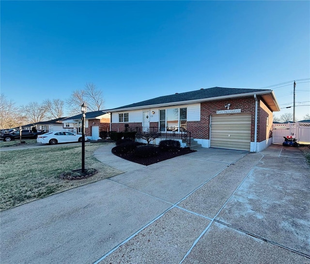 single story home with a front yard, fence, driveway, an attached garage, and brick siding