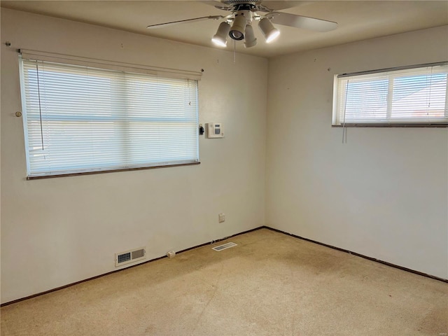 spare room with visible vents, light carpet, baseboards, and a ceiling fan