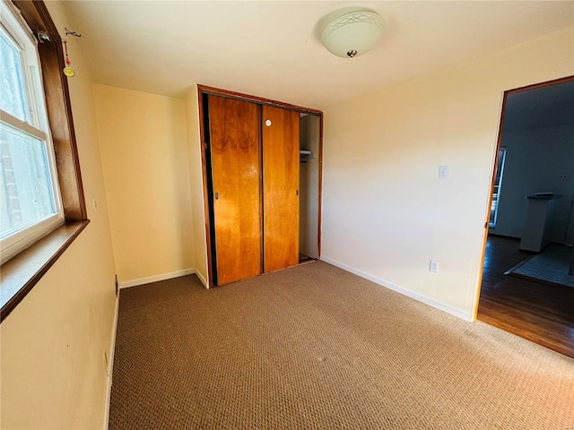 unfurnished bedroom featuring baseboards, a closet, and carpet floors