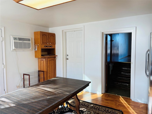 dining area featuring an AC wall unit and light wood-style flooring