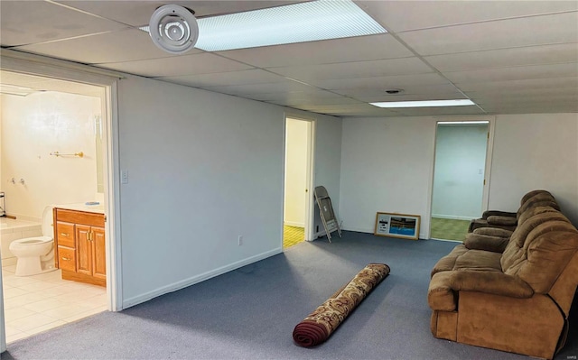 living area featuring light tile patterned floors, a drop ceiling, baseboards, and light colored carpet