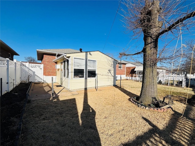 rear view of property featuring a lawn and a fenced backyard