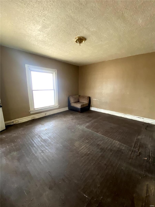 spare room with dark wood finished floors, a textured ceiling, and baseboards