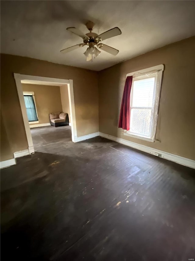 empty room featuring a ceiling fan and baseboards