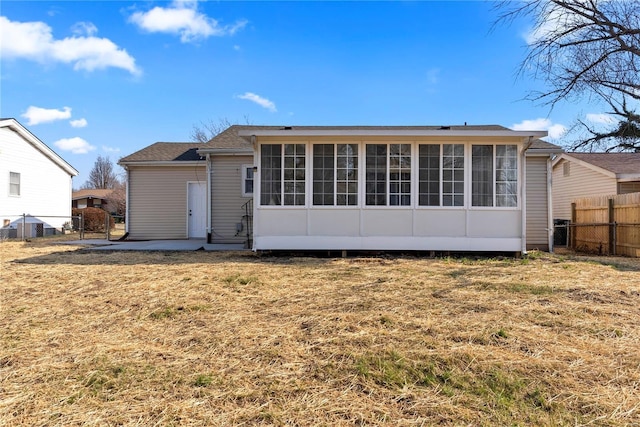 rear view of house featuring a yard, a sunroom, and fence