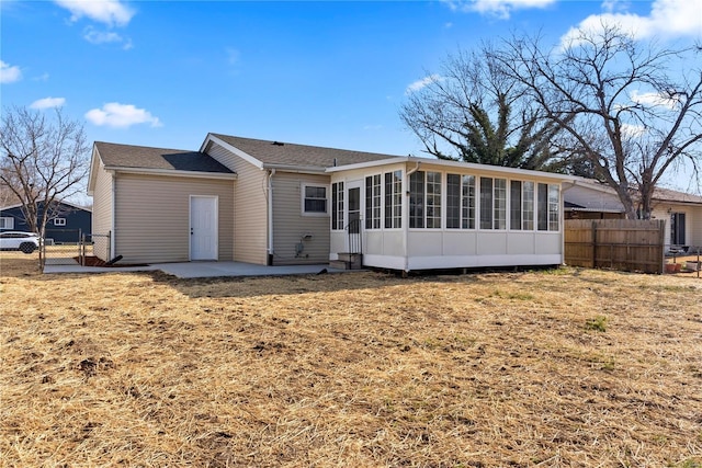 rear view of property with a gate, a patio area, fence, and a sunroom