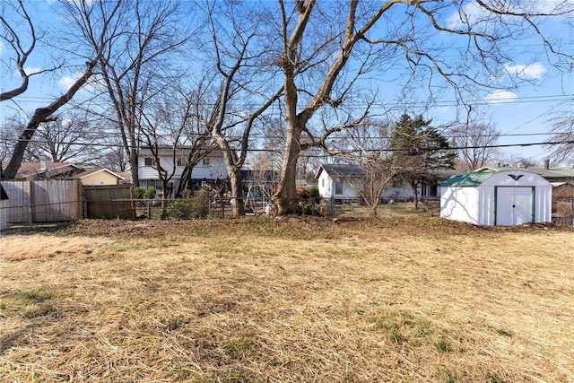 view of yard with fence, an outbuilding, and a shed