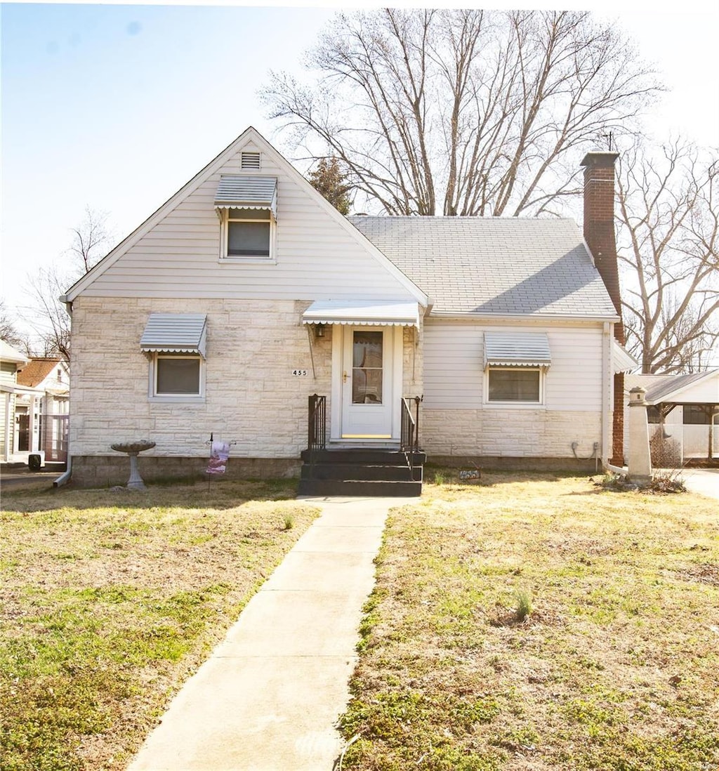 bungalow-style house featuring entry steps, a chimney, and a front lawn