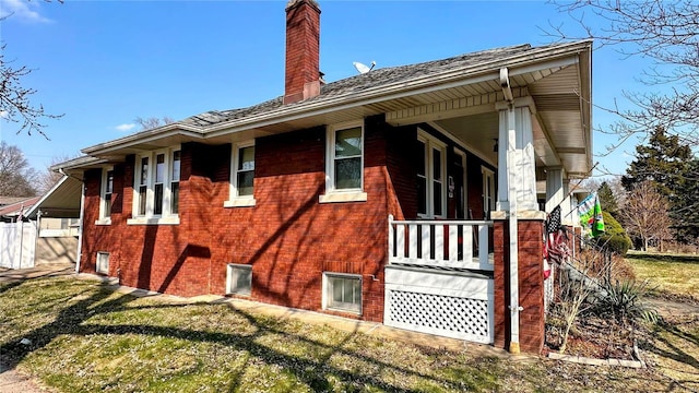 view of side of home featuring a lawn, a porch, and a chimney