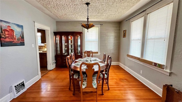 dining area with visible vents, baseboards, a textured ceiling, and light wood finished floors