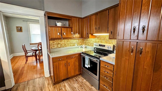 kitchen with electric range, light wood finished floors, open shelves, tasteful backsplash, and light countertops