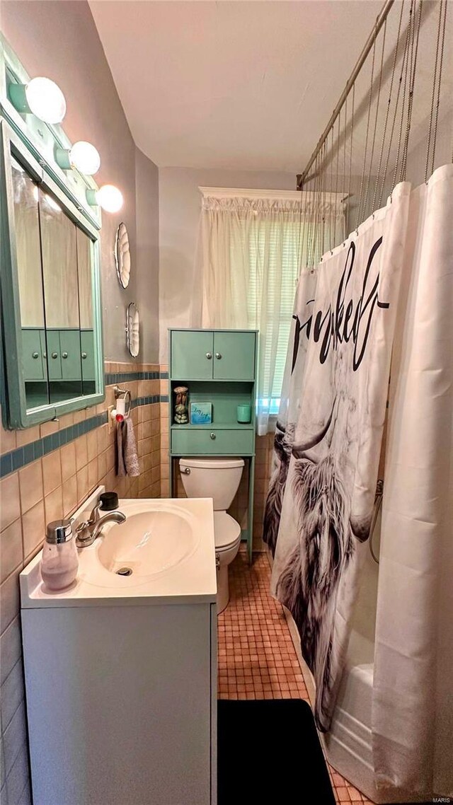 bathroom featuring a wainscoted wall, toilet, tile walls, shower / tub combo, and vanity