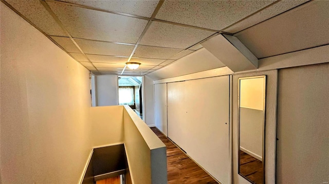 hall with dark wood-type flooring and a paneled ceiling